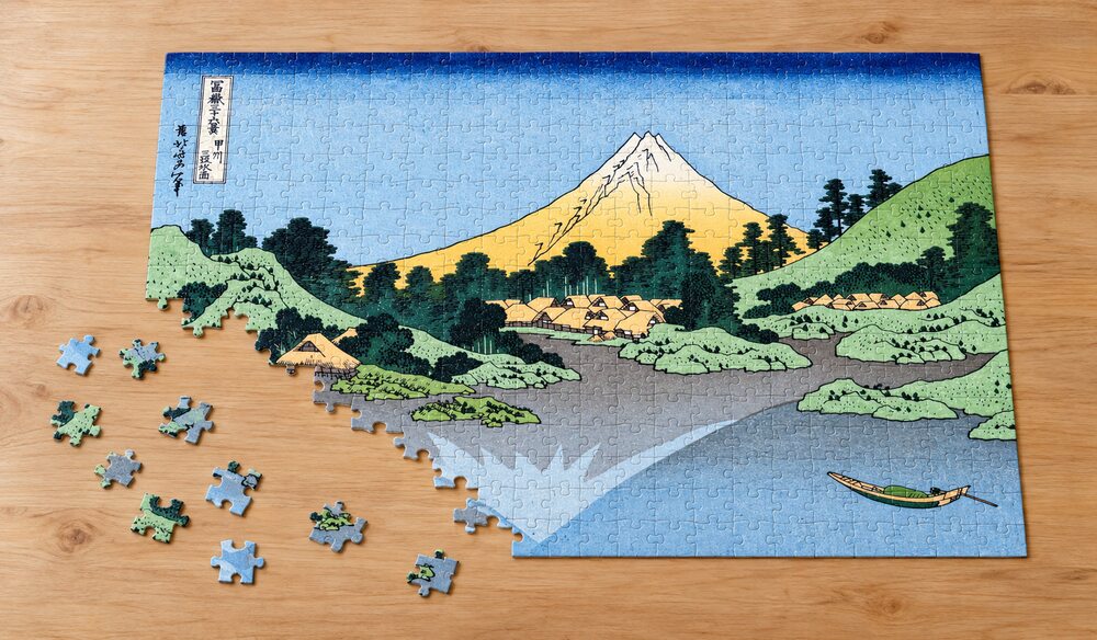 葛飾北斎「富嶽三十六景 甲州三坂水面」の組み立て途中のジグソーパズルを卓上に置いたイメージ