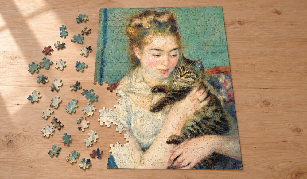 ルノワール「猫を抱く女性」の組み立て途中のイメージ。顔を寄せる女性と縞猫、猫を包む腕と手の形、白い服と青緑の背景を楽しむアートパズル