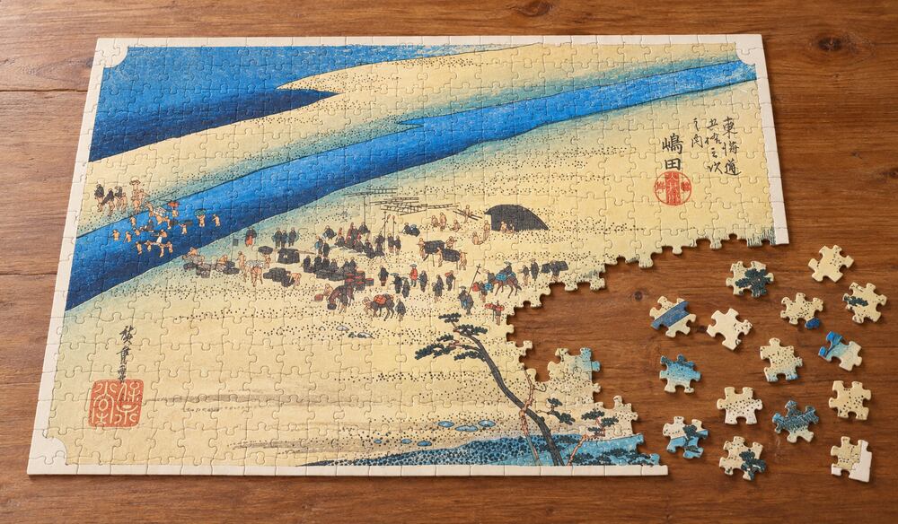歌川広重「東海道五十三次 嶋田宿 大井川駿岸」を絵柄にした、組み立て途中のジグソーパズルのイメージ