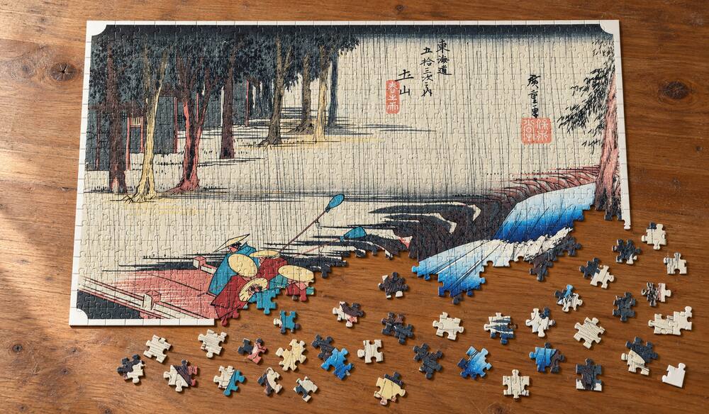 歌川広重「東海道五十三次 土山宿 春之雨」を絵柄にした、組み立て途中のジグソーパズルのイメージ