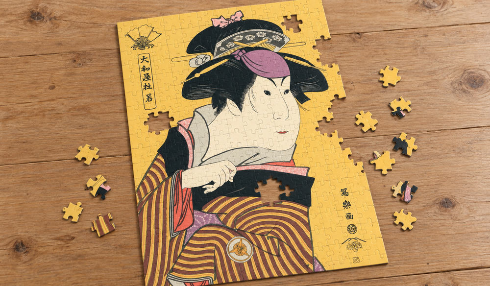 東洲斎写楽「四世岩井半四郎の田舎娘」を絵柄にした、組み立て途中のジグソーパズルのイメージ