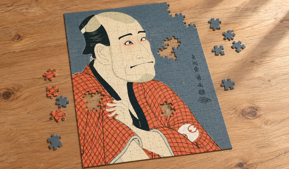 東洲斎写楽「嵐竜蔵の金貸石部金吉」を絵柄にした、組み立て途中のジグソーパズルのイメージ
