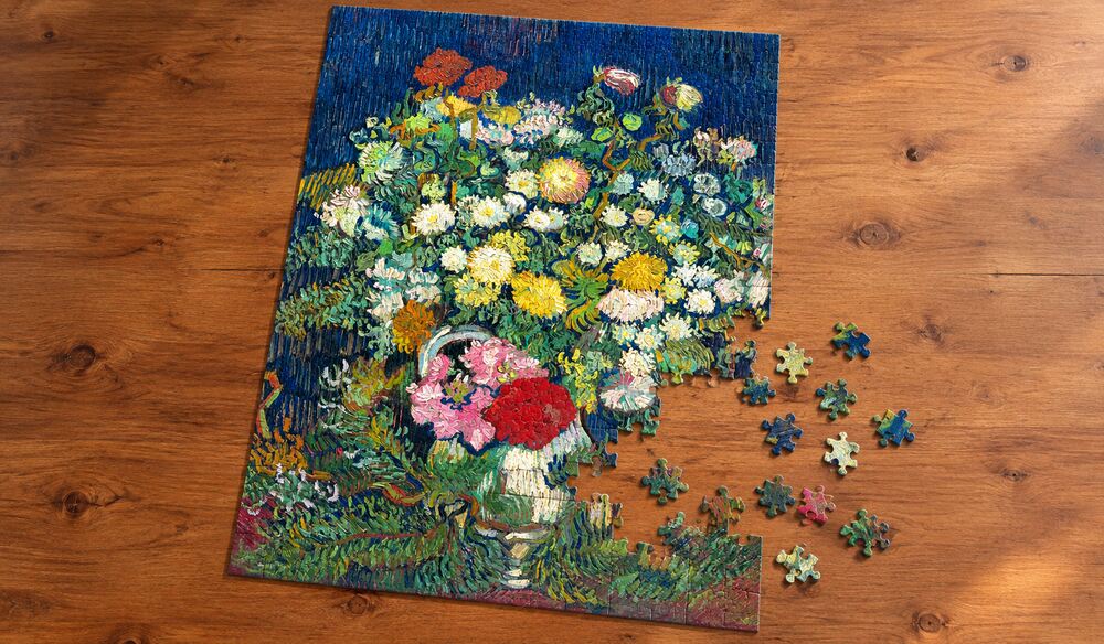 ゴッホ「花瓶の菊と野の花々」の組み立て途中を表したアートパズルのイメージ。暗い青を背景に広がる白・黄・赤・桃色の花を手がかりに楽しむ場面