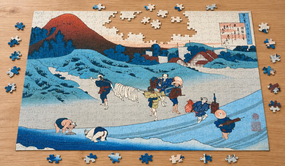 葛飾北斎「百人一首うはかえと起 持統天皇」を絵柄にした、組み立て途中のジグソーパズルのイメージ